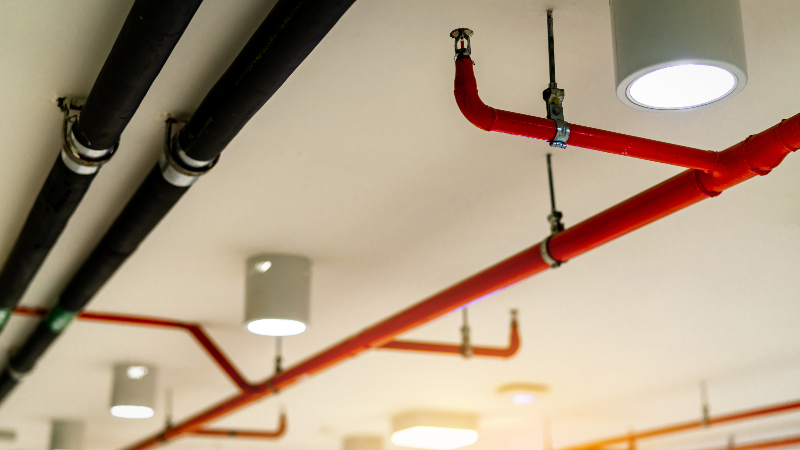 A fire sprinkler system with red pipes installed on a ceiling.